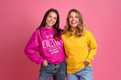 2 Frauen mit pinkem und gelbem Pullover vor rosanem Hintergrund 